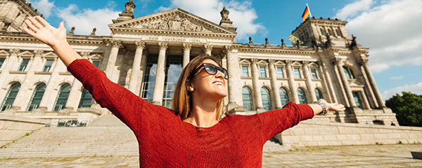 An Overview of Living in Germany - An image of a cheerful woman outside of a large building near Bun