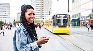 Transport Options in Germany - An image of a young woman walking in Berlin, Germany with a tram in t