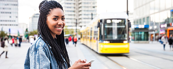 Transport Options in Germany - An image of a young woman walking in Berlin, Germany with a tram in t