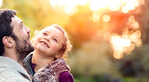 Support for Parents in Germany - An image of a father holding his young daughter within an outdoor s