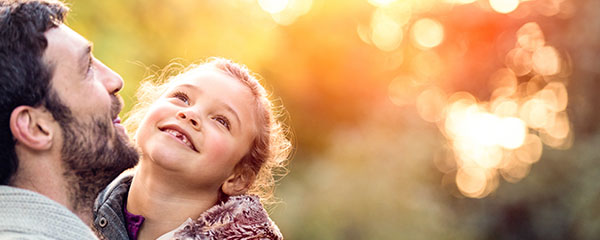 Support for Parents in Germany - An image of a father holding his young daughter within an outdoor s