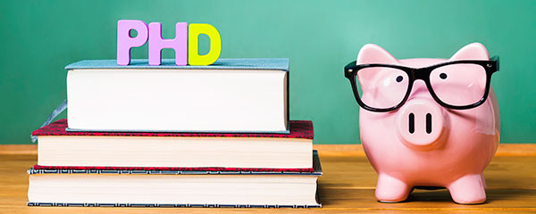 PhD degree theme with textbooks and piggy bank with glasses on green chalkboard background